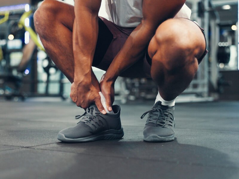 Man holding his foot in pain to show why feet hurt after workouts.