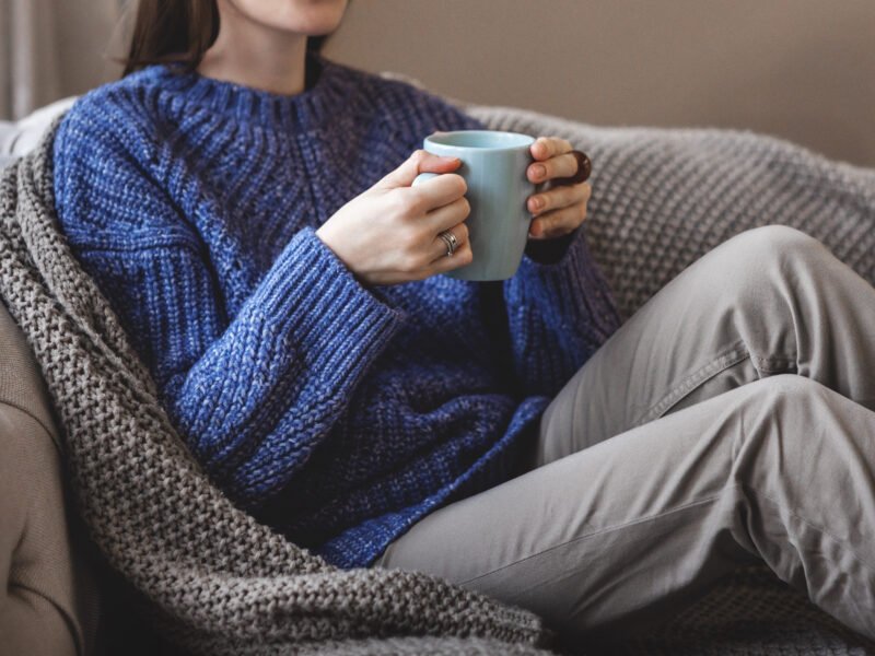 A woman relaxing at home with a warm drink, showing how small comfort upgrades improve daily well-being.