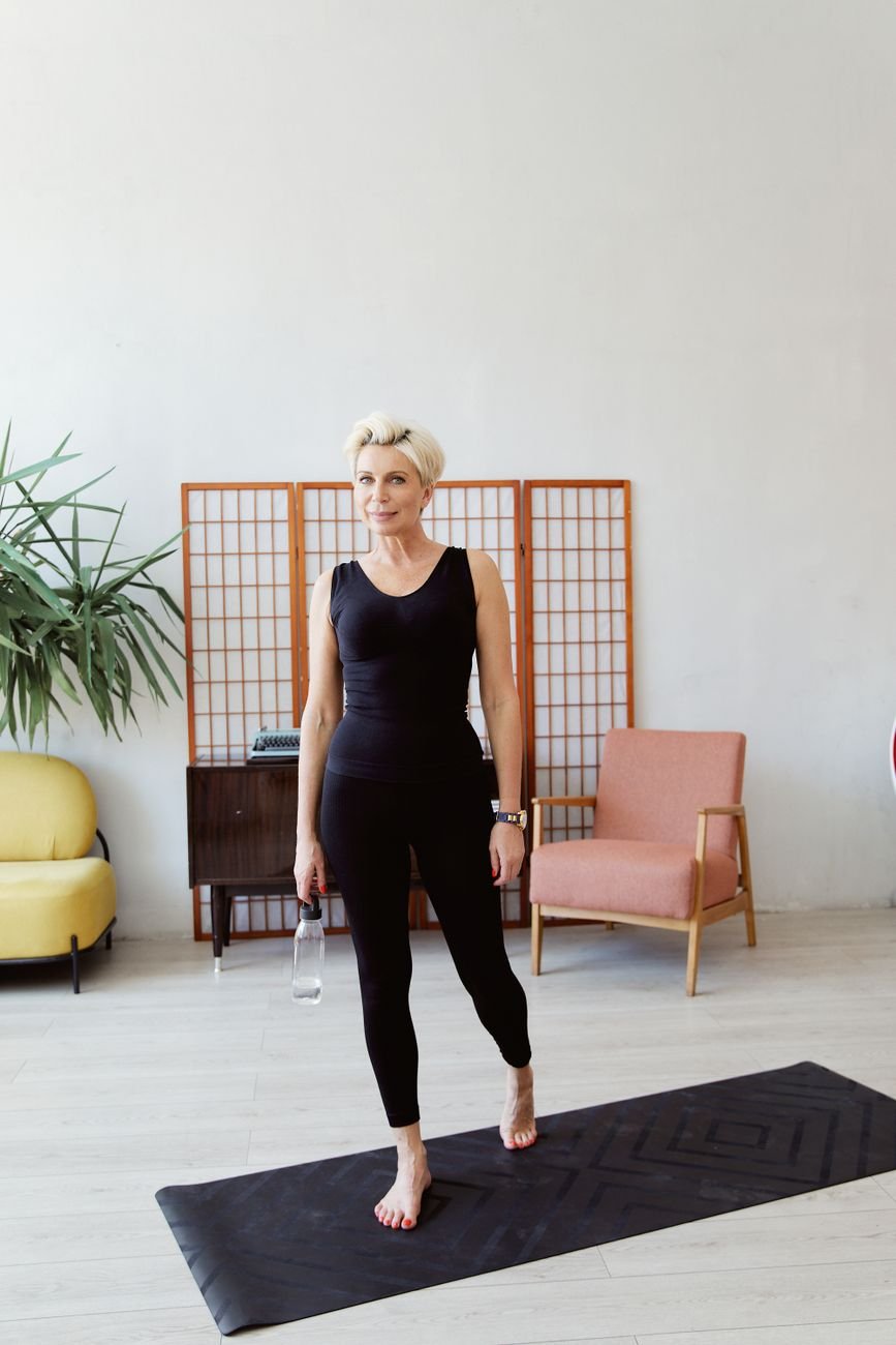 Chair yoga for seniors: older woman standing tall at home for supported standing poses