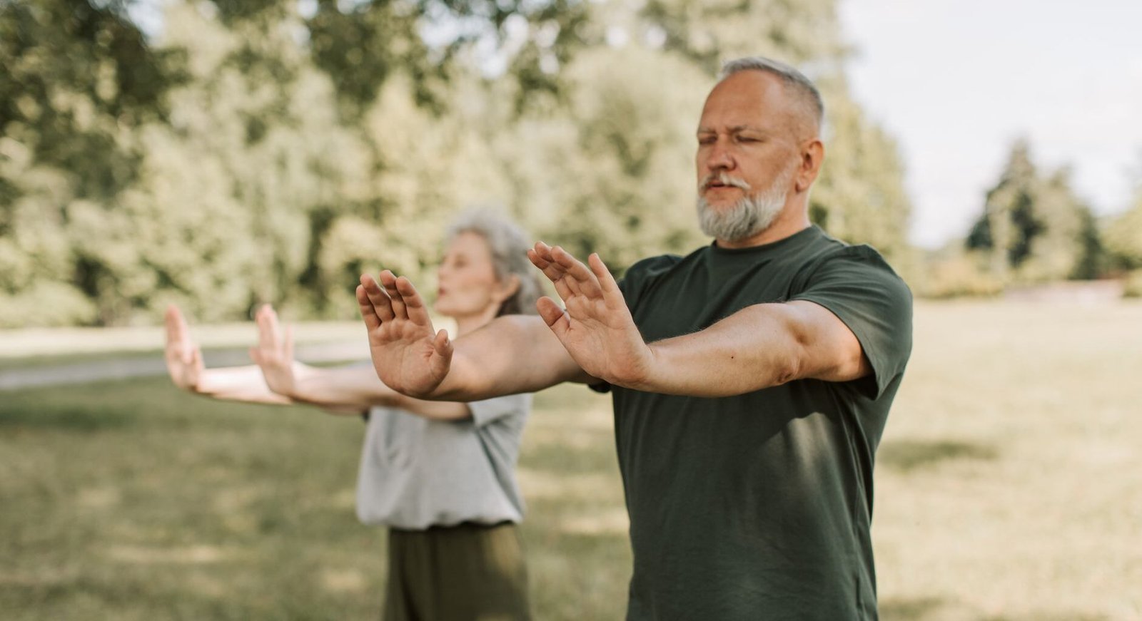 Tai chi lymphatic walking: elderly couple doing yoga with their arms outstretched